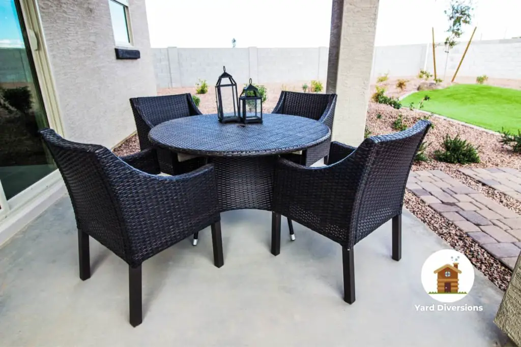 relaxing patio set with black chairs and table with an open backyard and little grass
