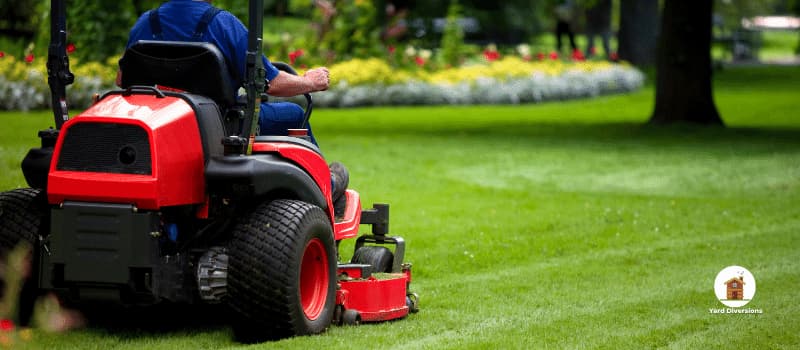 man cleaning up yard on a riding lawnmower