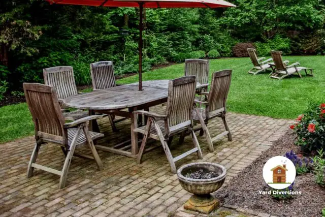 wooden patio set on a paver patio with a grass yard