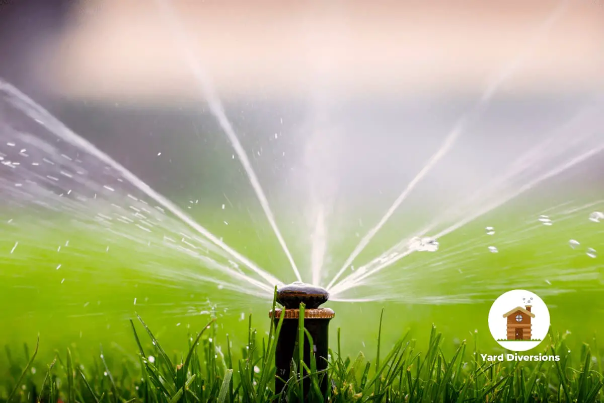 Close up of a lawn sprinkler out and spraying on the green grass