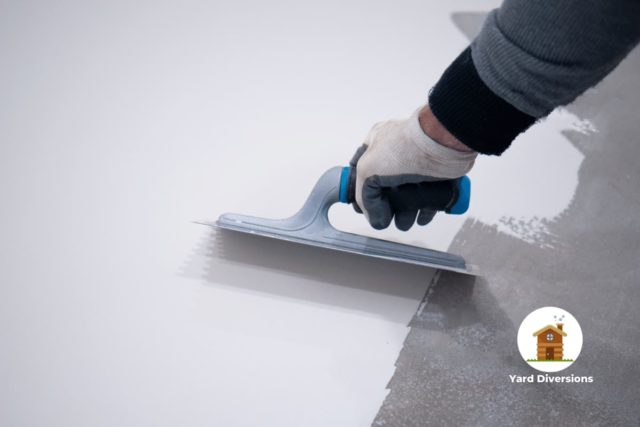 worker painting white polyurethane resin on a concrete floor