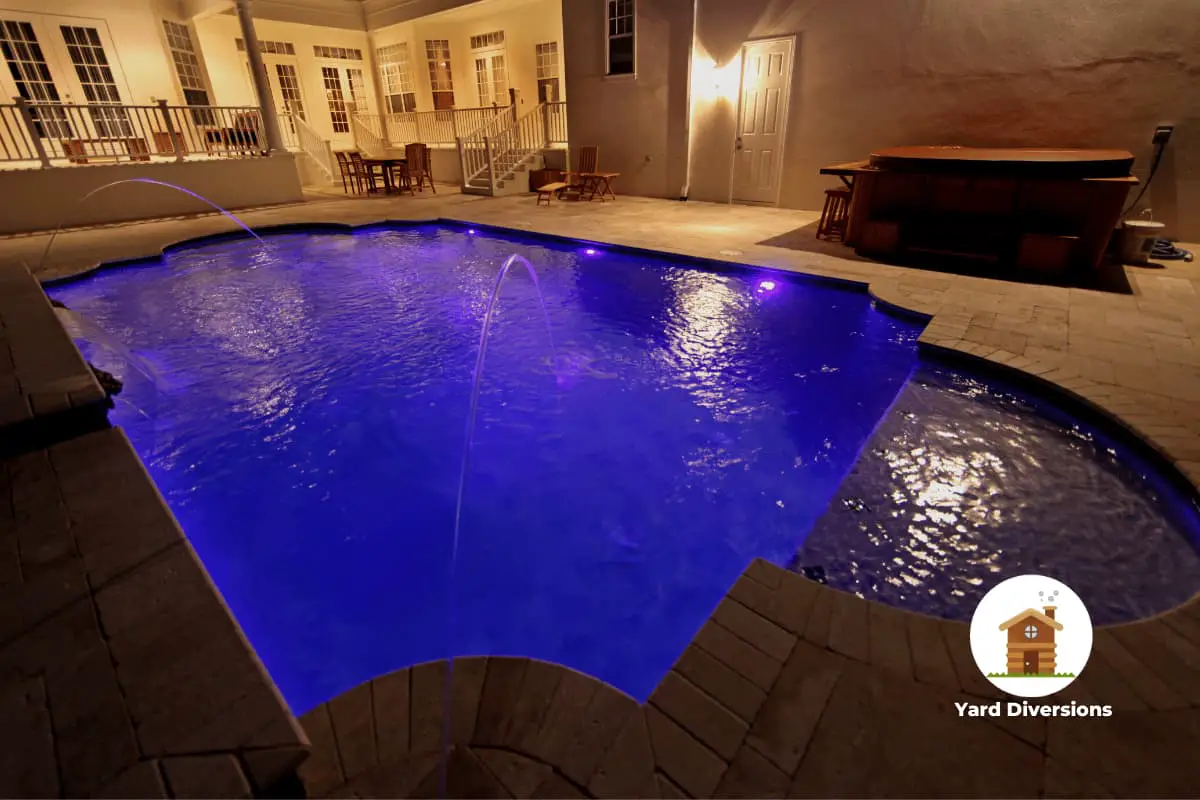 Amazing blue backlit pool at night with a travertine pool deck around it