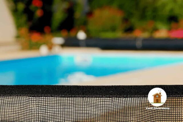 Close up of a mesh pool fence with a blurry pool in the background