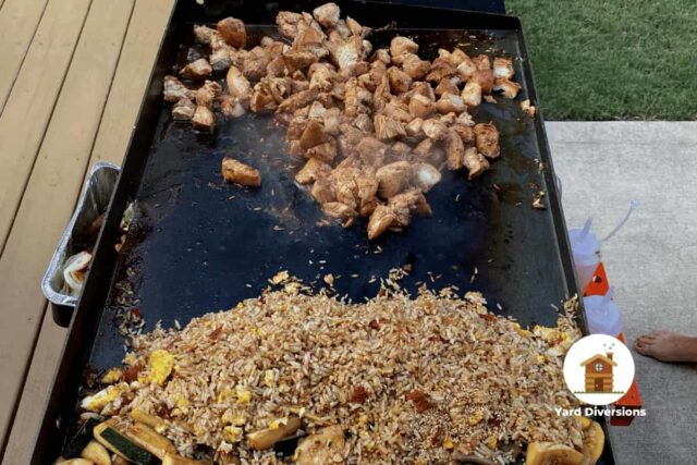 A flat top griddle cooking chicken from the back deck