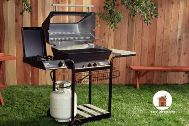 Grill against a wooden fence with a propane canister below