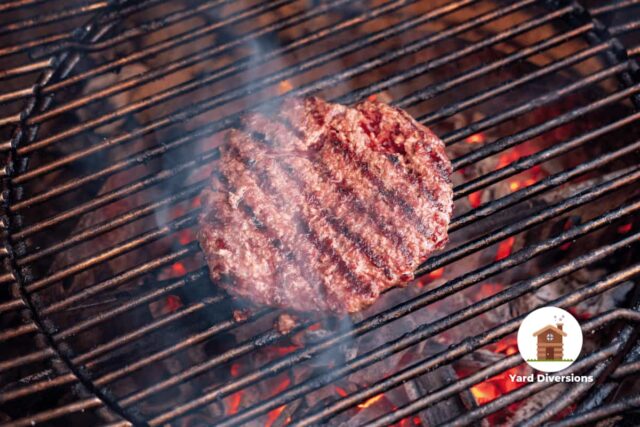 Single hamburger on a grill starting to cook