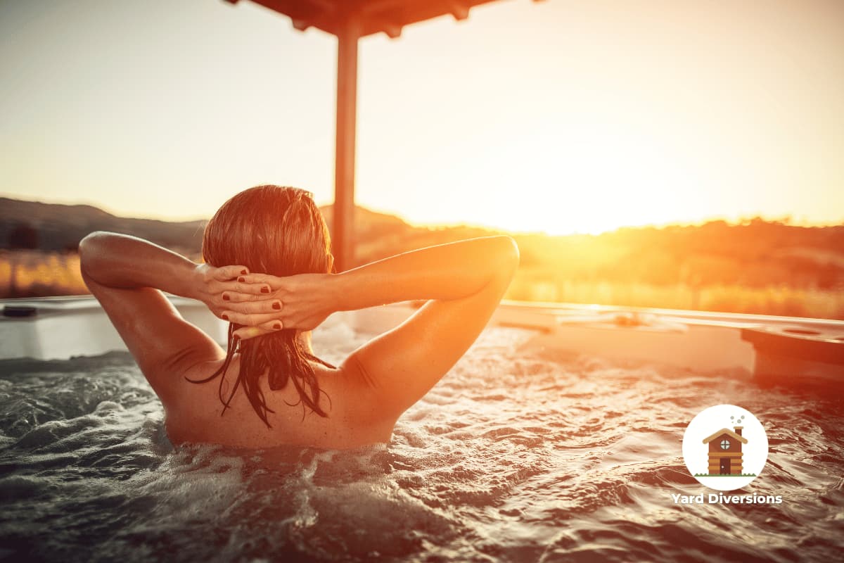 Woman relaxing in a hot tub placed under a pergola on a back patio