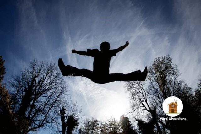 Man silhouetted against the sky bouncing on a trampoline