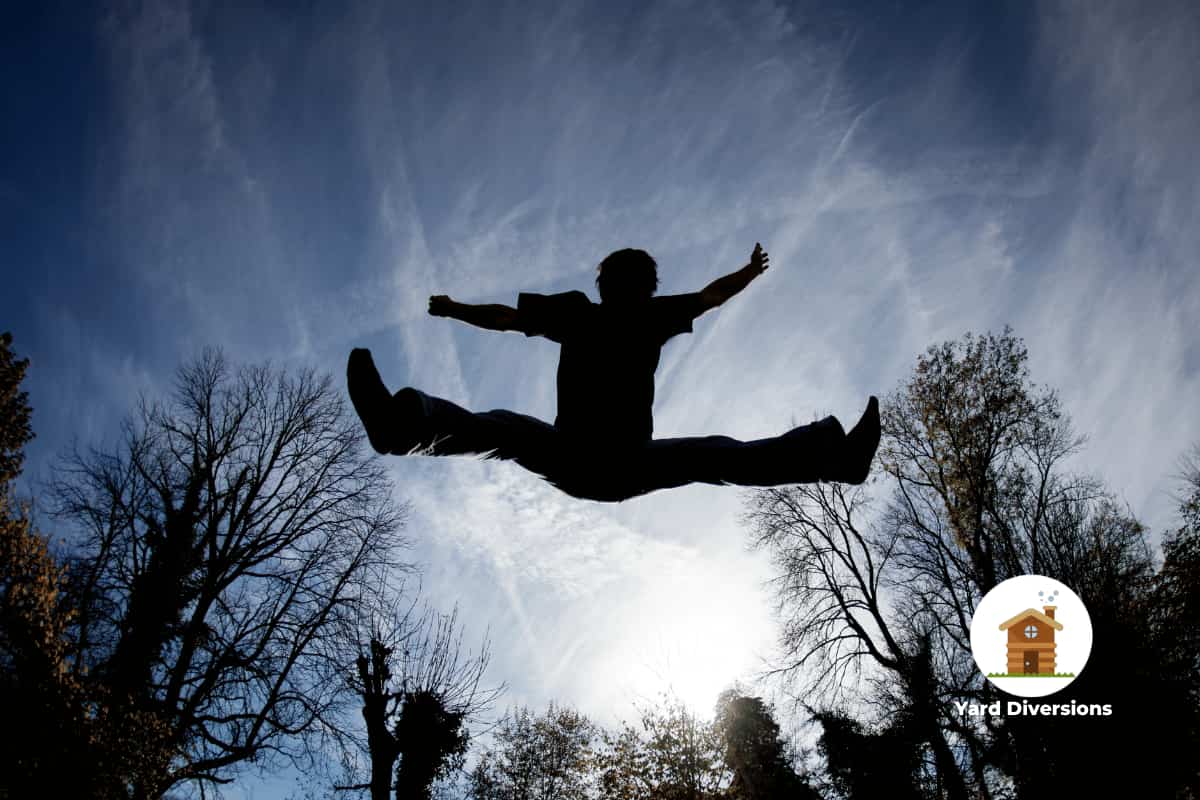Man silhouetted against the sky bouncing on a trampoline