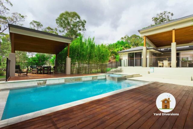 Amazing quality pool in a nice backyard with a pergola for relaxation and house in the background