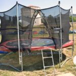 Setting up a trampoline in the grass with a nice protective net around it to protect from falls