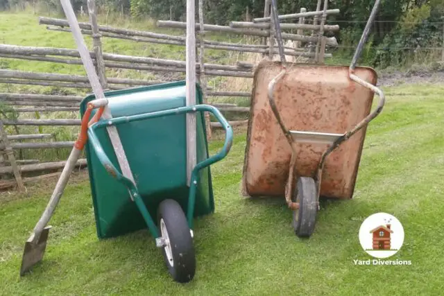 Pair of wheelbarrows being stored upright in the yard