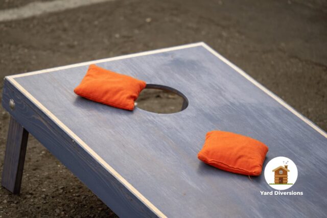 Nice wooden cornhole board with two red beanbags near the hole