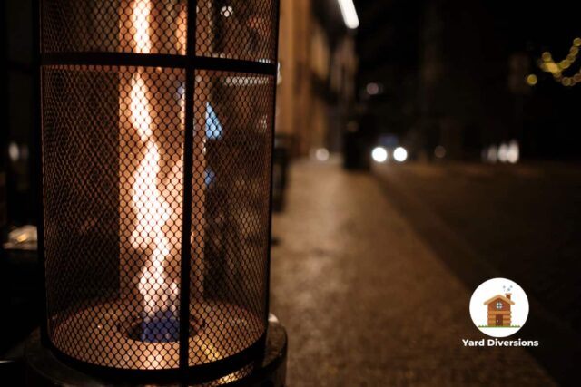 Patio heater generating flame on the sidewalk next to a street