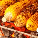 Corn cooking on a grill on top of coals