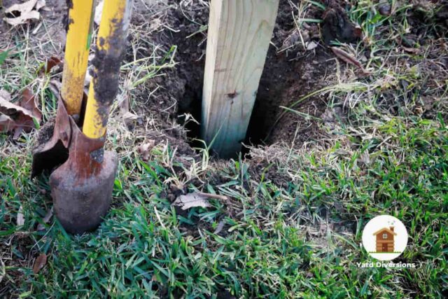Fence being placed in empty hole to be filled with concrete