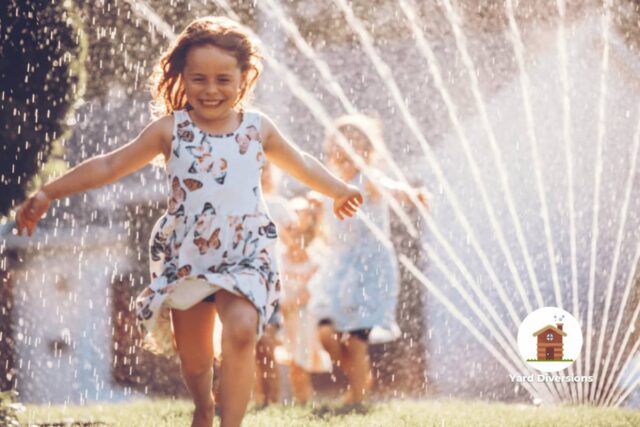 Kids in summer running through the sprinklers in the yard