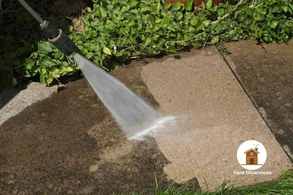 Close up of a pressure washer blasting awy grime and dirt on a concrete walkway