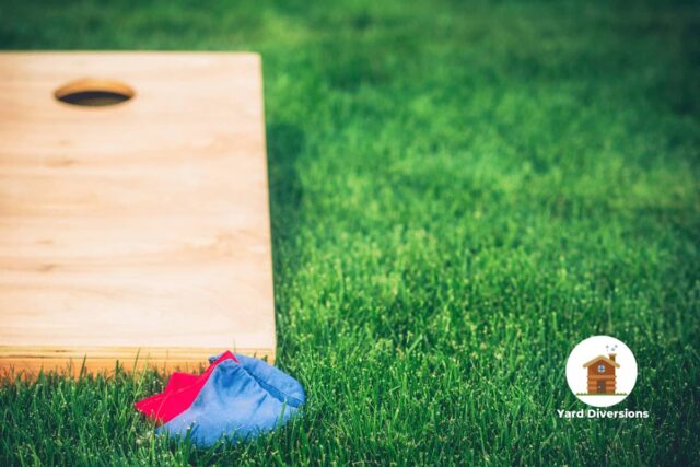 Cornhole board on grass with bean bags ready to toss