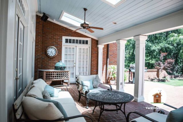 Outdoor back porch patio with outdoor seating and a large fan and table